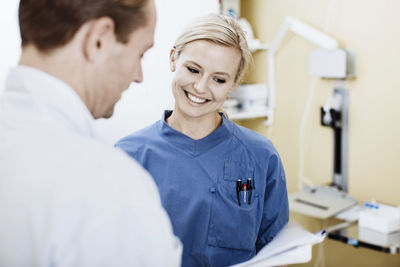 Young nurse with doctor reading report in hospital