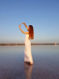 Woman standing at beach against sky