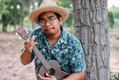 Man playing guitar while standing in forest