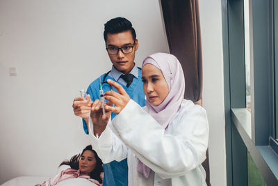 Young man holding woman standing against wall