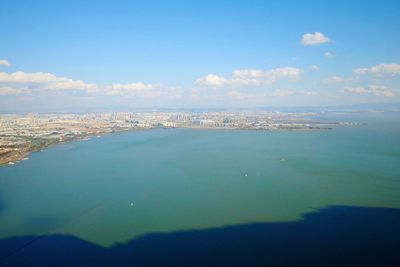 Aerial view of city by sea against sky