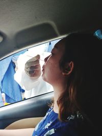 Portrait of girl in car taking antigen swab test for covid-19 detection