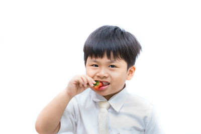 Portrait of boy eating food against white background