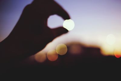 Close-up of silhouette hand against sky during sunset