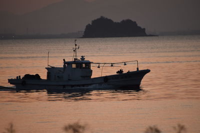 Boat sailing on sea against sky at sunset