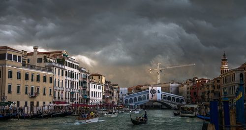 Boats in canal at city during stormy weather