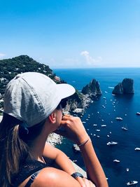 Side view of woman looking at sea against blue sky