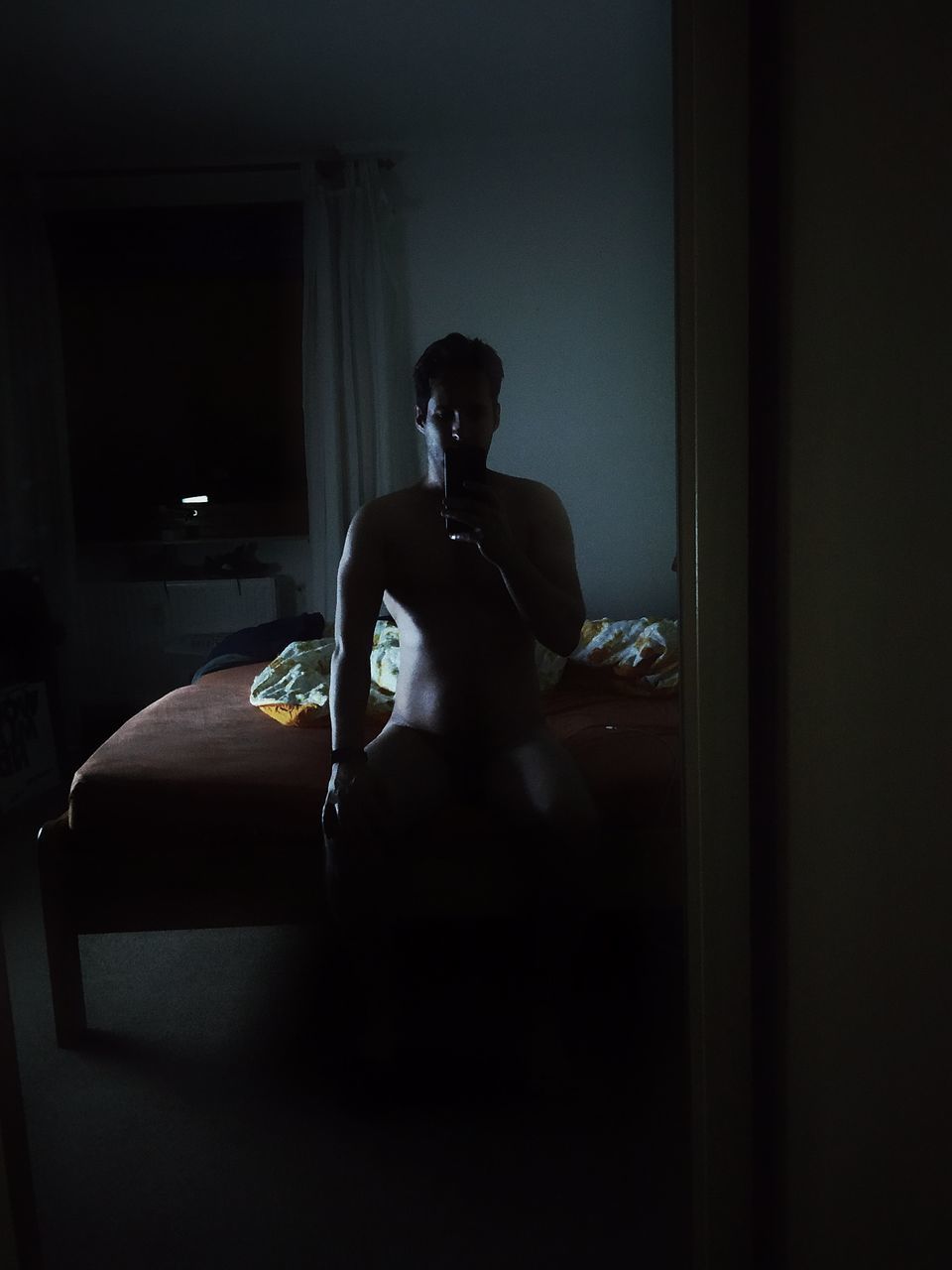 MAN SITTING BY WINDOW IN THE DARK