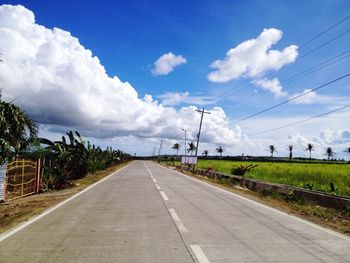 View of country road against cloudy sky