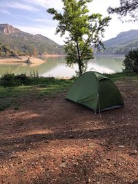 Scenic view of tent on mountain by lake against sky