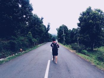 Rear view of man riding motorcycle on road