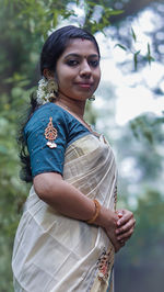 Portrait of young woman standing against trees in cultural dress 