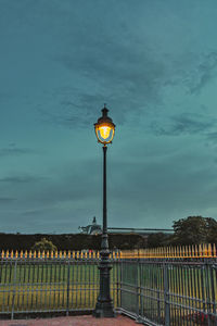 Illuminated street light against sky at dusk