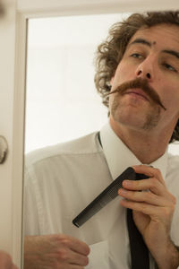 Reflection of businessman putting comb in pocket