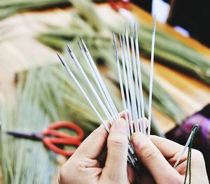 Close-up of hands holding sewing needles