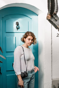 Portrait of young man standing against door