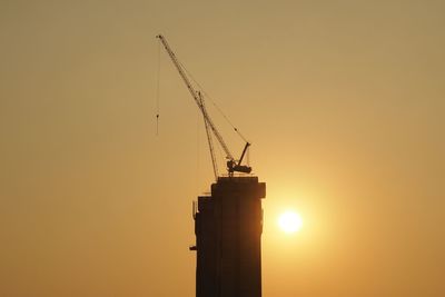 Silhouette crane against clear sky during sunset
