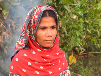 Portrait of young woman standing against plants