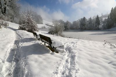 Snow covered field against cloudy sky