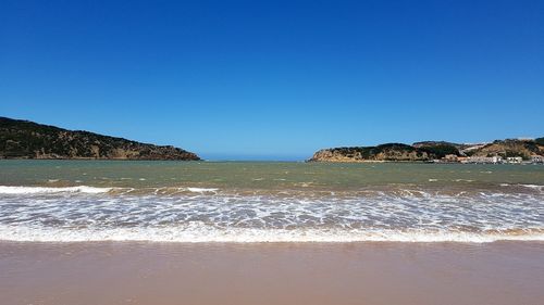 View of beach against clear blue sky
