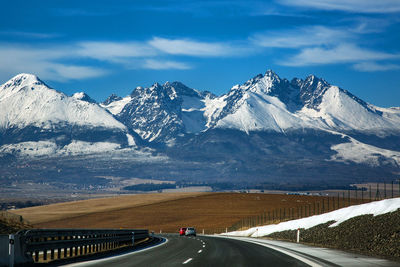 Road by mountains against sky