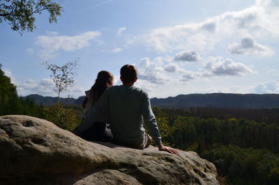 Rear view of people on rock against sky