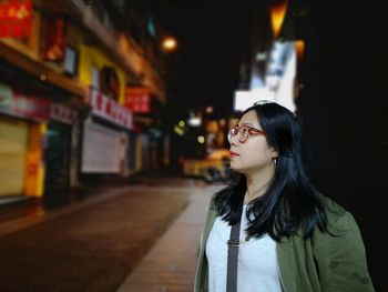 Woman looking away while standing at night