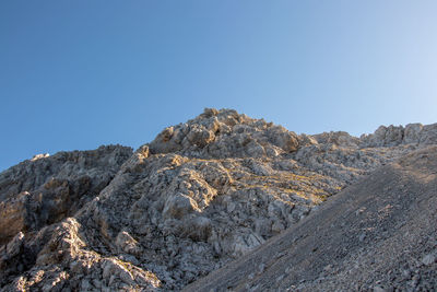 Low angle view of rock formations against clear blue sky