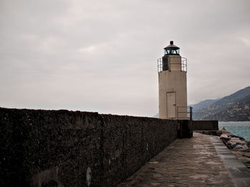 Lighthouse by building against sky