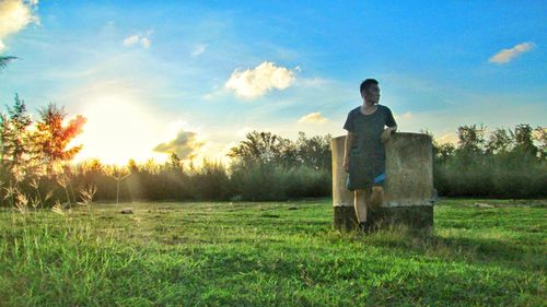 Man standing on field against sky during sunset