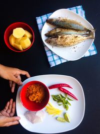 Cropped hand holding ingredients in plate over table