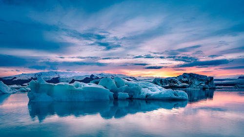 Frozen lake against sky during sunset