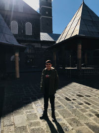 Full length portrait of man standing against building