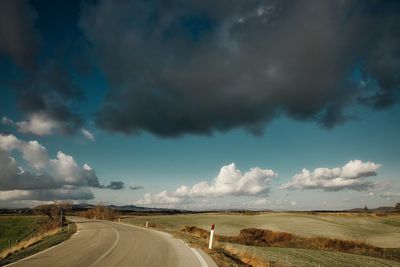 Road amidst field against sky