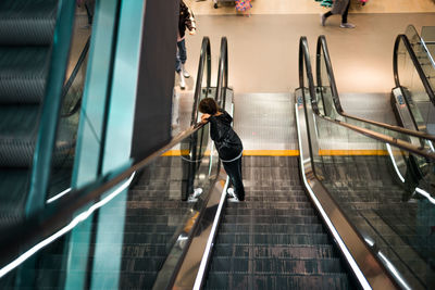 High angle view of boy standing on escalator