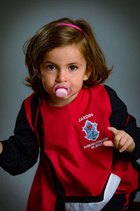 Portrait of cute girl standing against wall