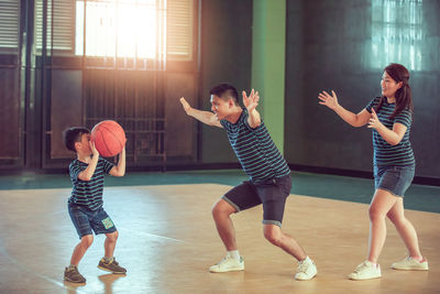 Family playing basketball on sports court