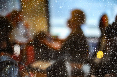 Reflection of people on wet glass window in rainy season