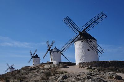 Low angle view of windmill on hill against sky