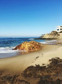 Scenic view of beach against clear blue sky