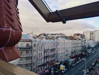 Cars moving on road by buildings seen from window