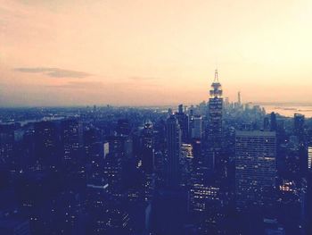 Aerial view of city lit up against sky