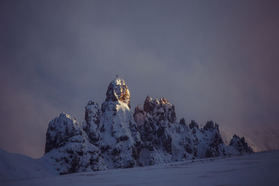 Low angle view of snowcapped mountains against cloudy sky