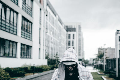 Man standing against buildings during rain