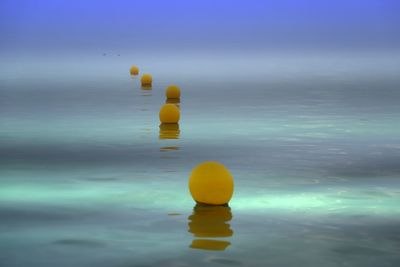 Close-up of yellow ball in sea against sky