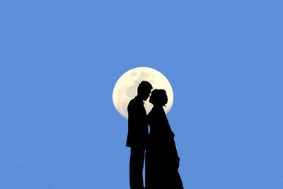 Silhouette couple standing against moon