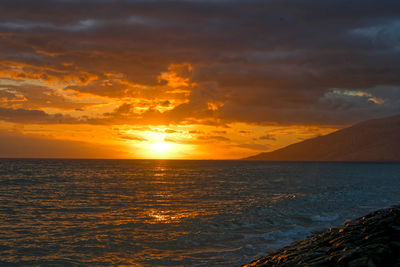 Scenic view of sea against dramatic sky during sunset