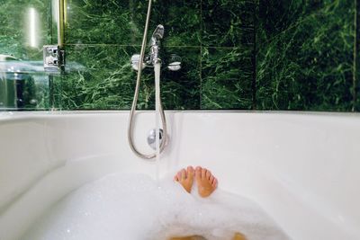 Low section of woman relaxing in the bathtub