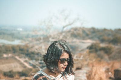 Portrait of young woman in sunglasses against sky