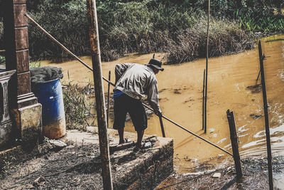 Rear view of man working on fence